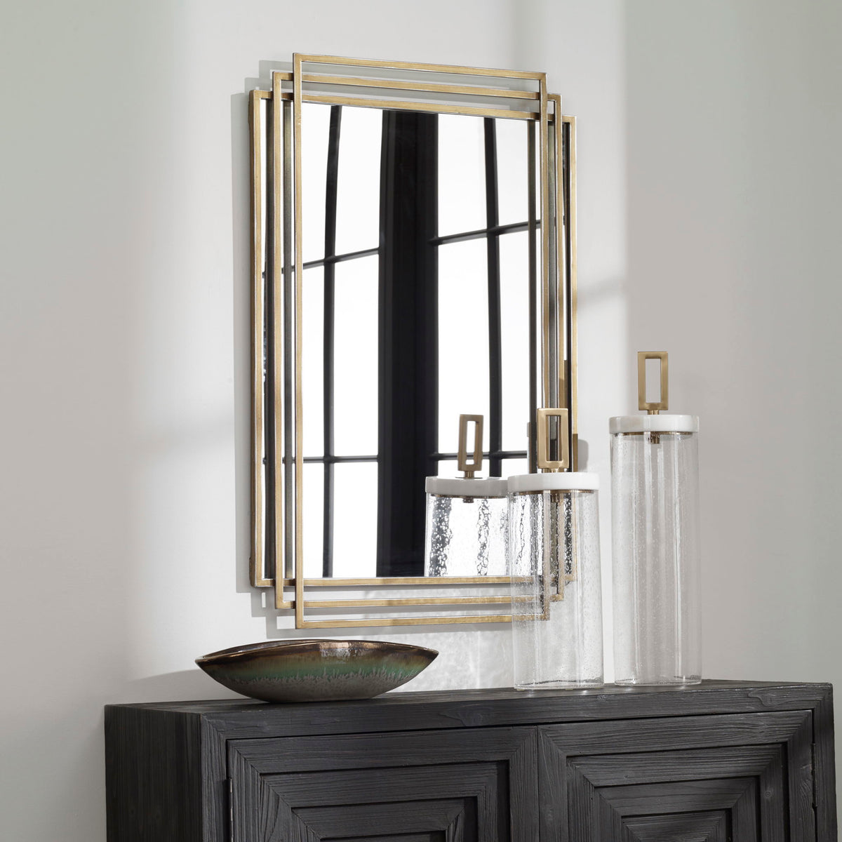 Uttermost Amherst wall mirror with a sleek, modern frame hanging on a wall, showcasing contemporary home decor style.