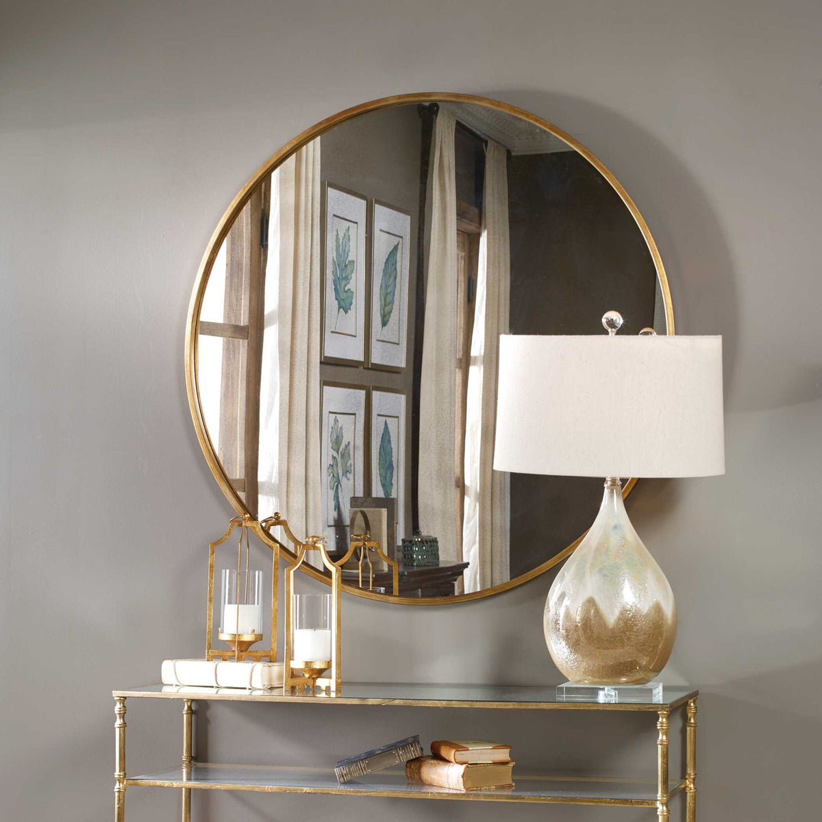 Uttermost Junius round wall mirror with a sleek frame, hanging on a wall, reflecting a modern interior space.