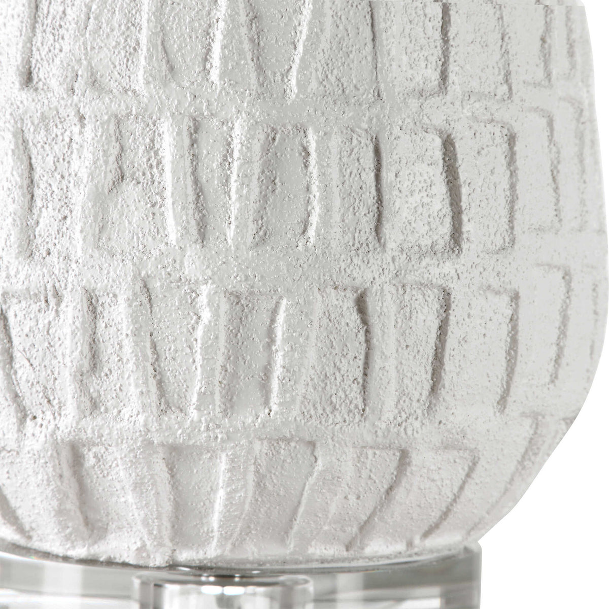 White textured Caelina table lamp by Uttermost with a sleek, modern design, featuring a rounded base and fabric shade.