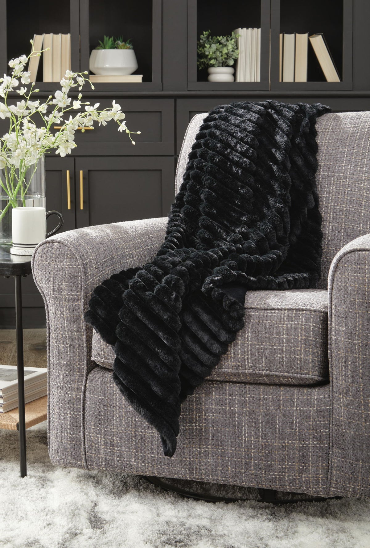 Soft beige Alsonwell throw blanket by Signature Design by Ashley®, draped over a cozy armchair.