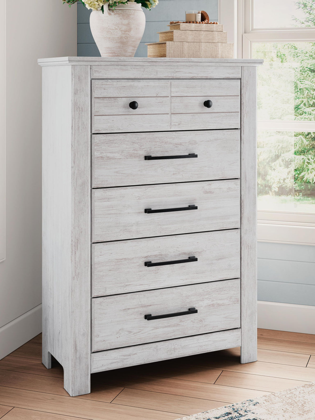 Signature Design by Ashley Makidern five-drawer accent chest with wood finish and modern hardware, standing on four sturdy legs.