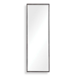 Uttermost Callan black leaner mirror with sleek frame, standing tall against a wall in a modern interior setting.