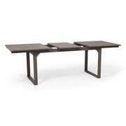 Outdoor expandable acacia wood dining table with U-shaped legs by Noble House, showing the table's natural wood grain and expanded size.