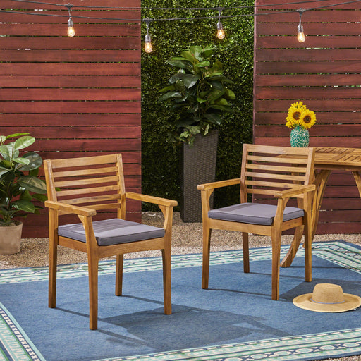 Set of two outdoor dining chairs by Noble House with slat back and acacia wood frame in gray and teak finish.