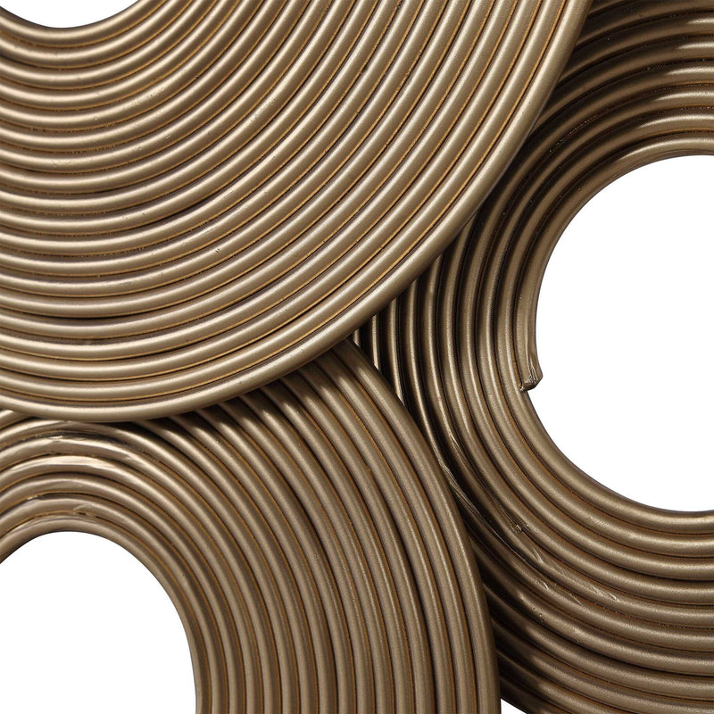 Gold rings wall decor by Uttermost, featuring overlapping gold metal rings mounted on a neutral wall for modern interior style.