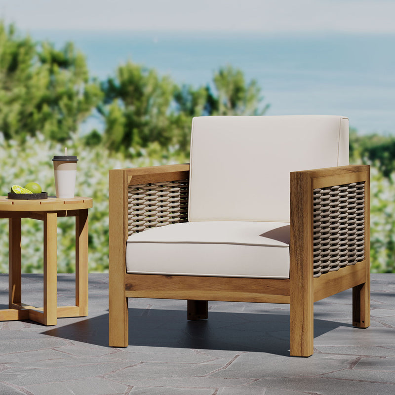 Noble House outdoor acacia wood arm chair with woven wicker accents and comfortable cushions in a natural garden setting.