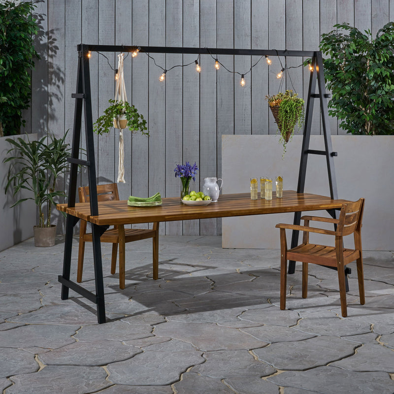 Noble House Huckleberry outdoor dining table with acacia wood finish, plant hanger, and teak accents for patio or garden.