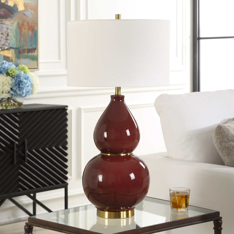 Uttermost gourd-shaped table lamp with a smooth, rounded ceramic base and a neutral fabric lampshade on a wooden surface.