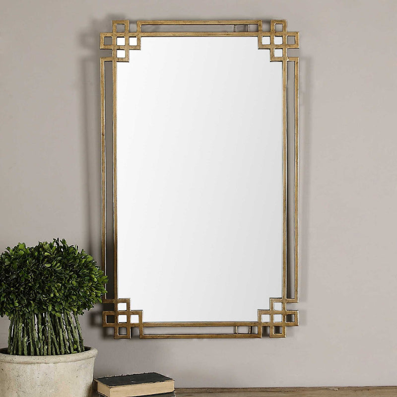 Uttermost Devoll wall mirror with antique gold finish, decorative rectangular frame, hangs on a wall.