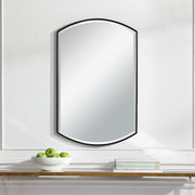Black shield-shaped iron wall mirror by Uttermost, featuring a bold, decorative frame with a reflective glass center.