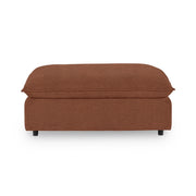 Classic Home Caplan upholstered ottoman with plush fabric and wooden legs, serving as a stylish accent or footrest.
