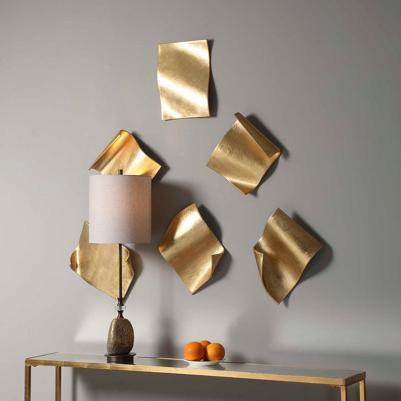 Set of six gold Fluttering Pages wall decor pieces by Uttermost, featuring abstract, fluttering leaf-shaped designs for wall decoration.