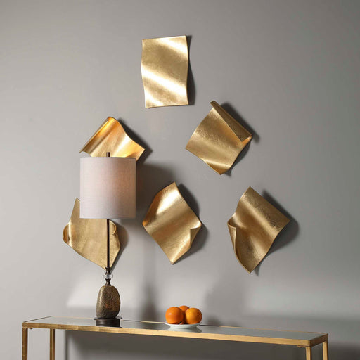 Set of six gold Fluttering Pages wall decor pieces by Uttermost, featuring abstract, fluttering leaf-shaped designs for wall decoration.