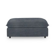 Classic Home Caplan upholstered ottoman with a cushioned top and wooden legs, ideal for living room or bedroom decor.