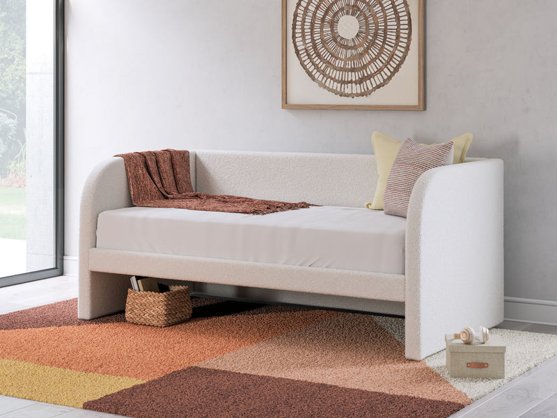 Upholstered Signature Design by Ashley® Arloster day bed with plush cushions and wooden frame, styled for a modern bedroom.