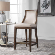 Uttermost Purcell beige counter stool with wooden legs and padded seat, suitable for kitchen or bar counter height.