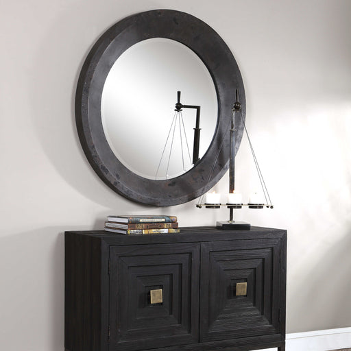 Round black industrial wall mirror by Uttermost with a sleek metal frame, suitable for modern or industrial decor.