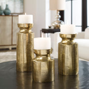Set of three Amina candleholders by Uttermost in antique brass, featuring elegant sculptural design for decorative display.