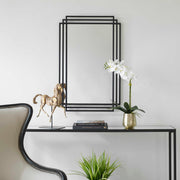 Uttermost Amherst wall mirror with a sleek, modern frame, hanging on a wall to showcase its stylish design.