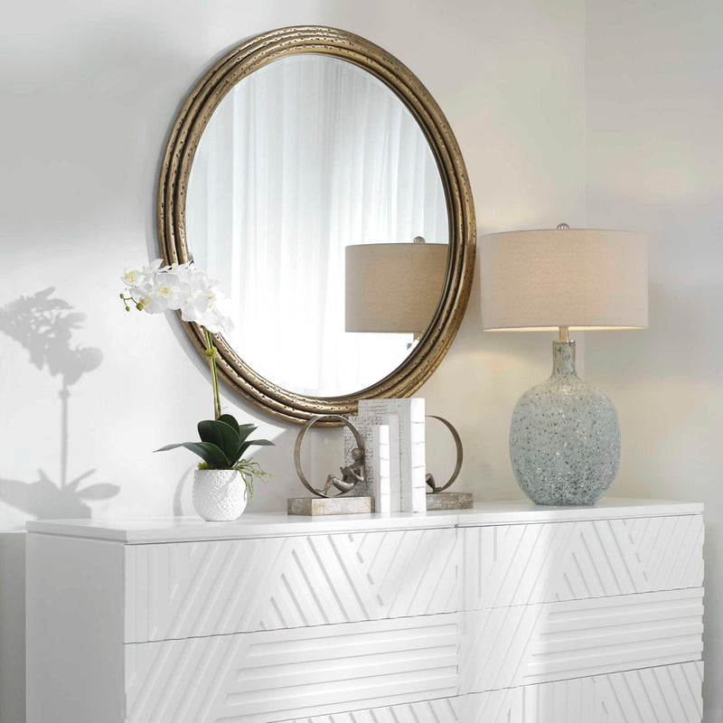 Uttermost Spera round wall mirror with a gold finish, featuring a sleek, modern design and a smooth circular frame.