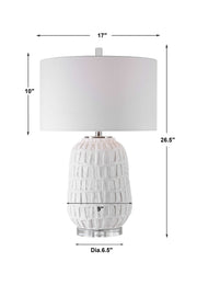 Uttermost Caelina textured white table lamp with a modern ceramic base and fabric shade on a wooden surface.