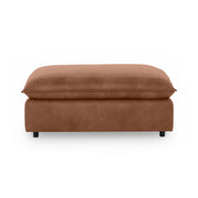 Classic Home Caplan upholstered ottoman with a plush fabric finish, serving as a versatile footrest or accent piece.