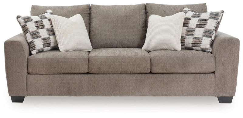 Benchcraft stationary sofa with plush cushions and modern design, featuring neutral fabric upholstery and wide armrests.