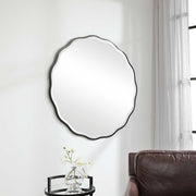 Uttermost Aneta round wall mirror with a sleek frame, mounted on a wall, showcasing modern and stylish home decor.