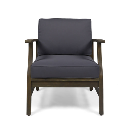 Noble House outdoor club arm chair with dark gray water-resistant cushion and slat panel design in a cozy patio setting