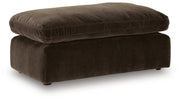 Benchcraft® Maxton Heights upholstered ottoman with plush fabric and wooden legs, used as a footrest or versatile accent piece.