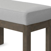 Simpli-Home Milltown upholstered ottoman bench with cushioned top and wooden legs, ideal for living room seating or footrest.