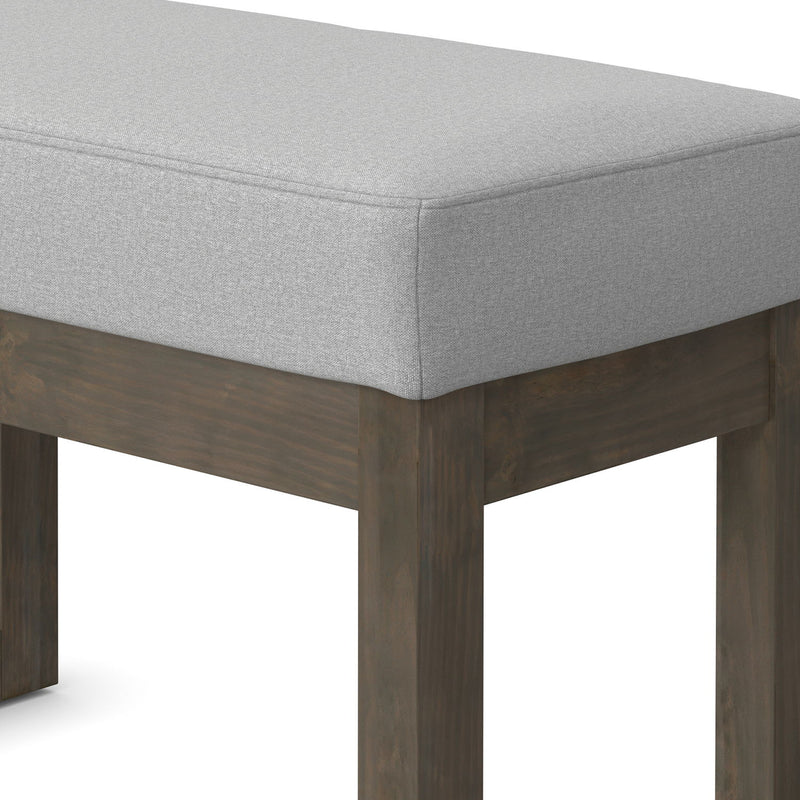 Simpli-Home Milltown upholstered ottoman bench with cushioned top and wooden legs, ideal for living room seating or footrest.