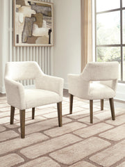 Set of two Benchcraft Marxmore dining upholstered arm chairs in beige and brown with cushioned seats and wooden legs.