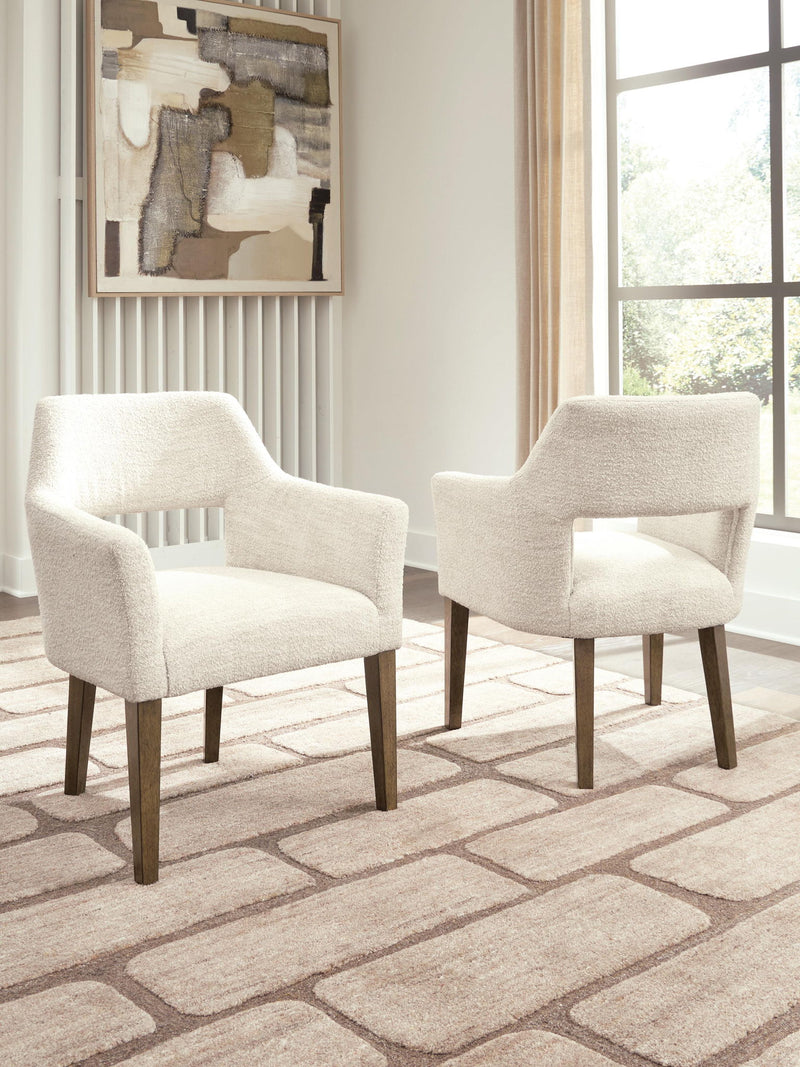 Set of two Benchcraft Marxmore dining upholstered arm chairs in beige and brown with cushioned seats and wooden legs.