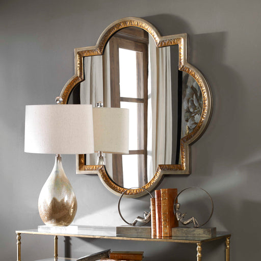 Uttermost Lourosa gold wall mirror with a sleek, modern design and a polished gold finish, hanging on a wall.