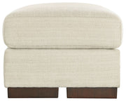 Signature Design by Ashley Maggie upholstered ottoman with a plush fabric top and wooden legs, versatile for living room decor.