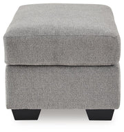Benchcraft® upholstered ottoman with plush fabric and tufted top, perfect for living room decor and extra seating.