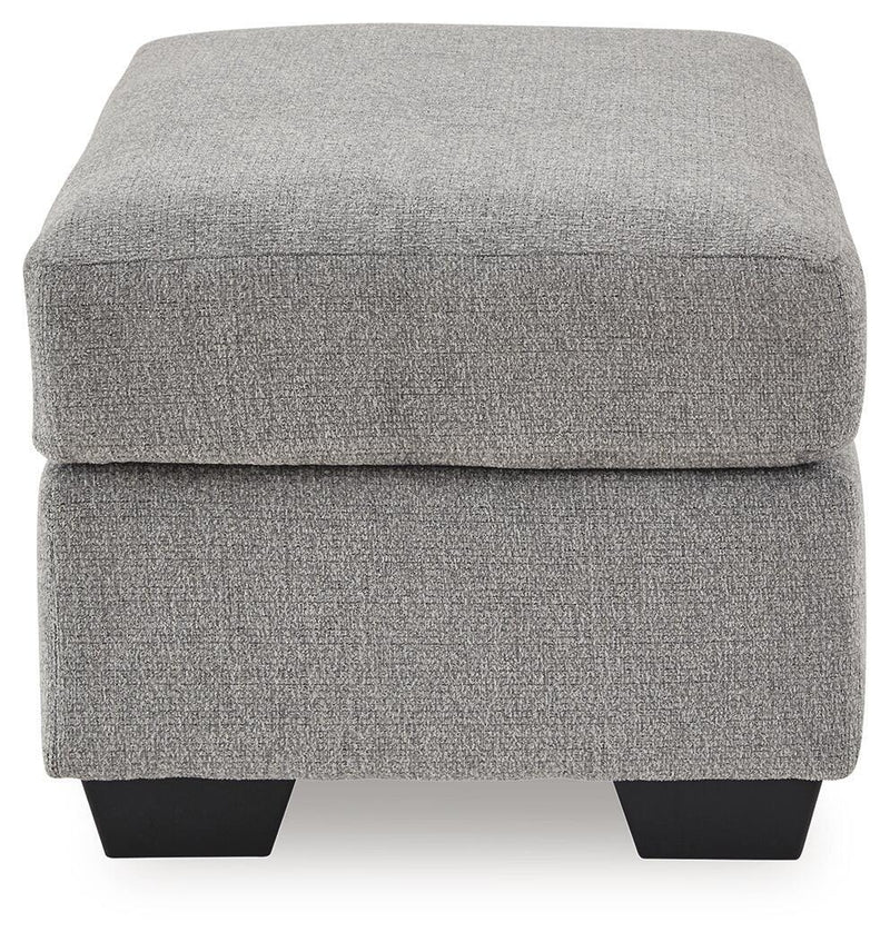 Benchcraft® upholstered ottoman with plush fabric and tufted top, perfect for living room decor and extra seating.