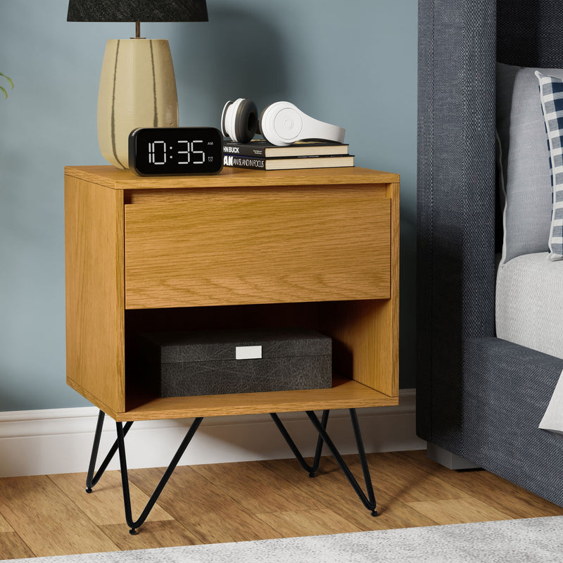 Simpli-Home Hunter accent nightstand with drawer and shelf, black wood finish, modern design, placed beside a bed in a bedroom setting.