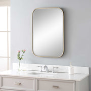 Uttermost Malay gold vanity mirror with a sleek, modern frame reflecting a stylish bathroom or bedroom decor.