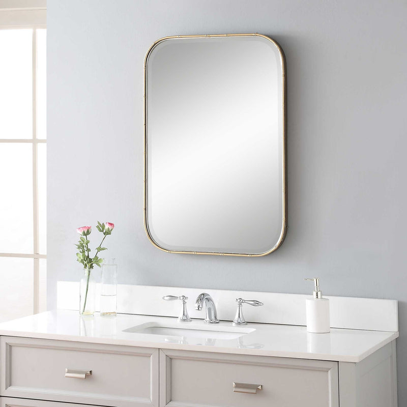 Uttermost Malay gold vanity mirror with a sleek, modern frame reflecting a stylish bathroom or bedroom decor.