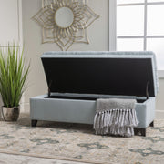 Noble House Juliana storage ottoman with birch wood legs, upholstered in neutral fabric, used as a footrest or extra seating.