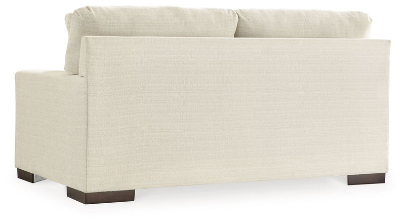 Signature Design by Ashley Maggie living room set with stationary chair and matching ottoman, upholstered in neutral fabric.
