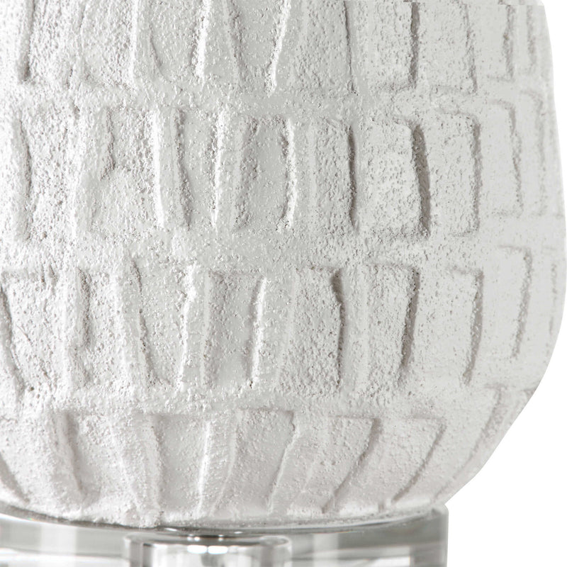 White textured Caelina table lamp by Uttermost with a sleek, modern design, featuring a rounded base and fabric shade.