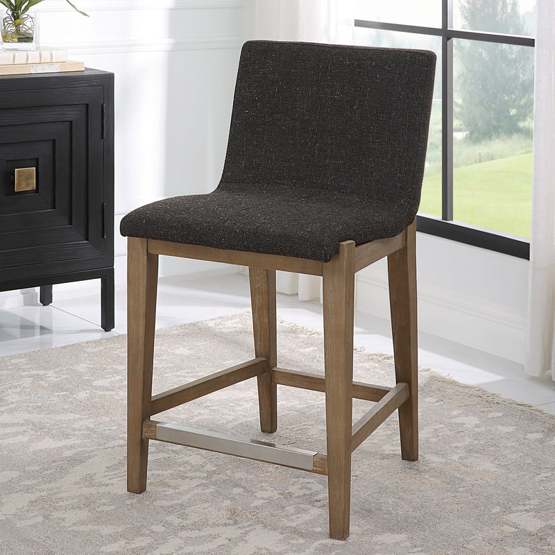 Uttermost Klemens counter stool with wooden frame and cushioned seat, 24-27 inch height, in a modern design.