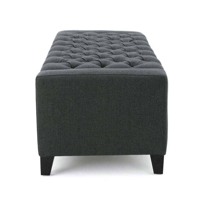 Dark gray Noble House storage ottoman with a tufted top, serving as a stylish and functional living room storage solution.