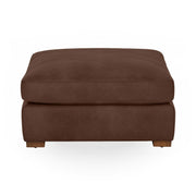 Classic Home Audrey upholstered ottoman with plush fabric and wooden legs, serving as a stylish footrest or accent piece.