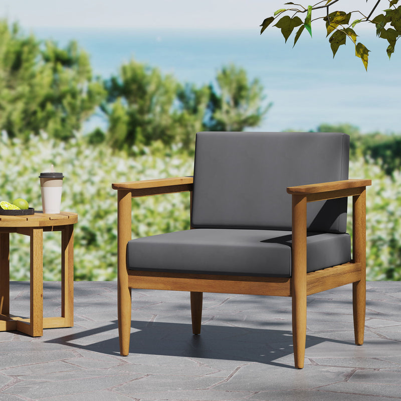 Dark gray outdoor club arm chair with teak acacia wood frame by Noble House, featuring cushioned seating and armrests.