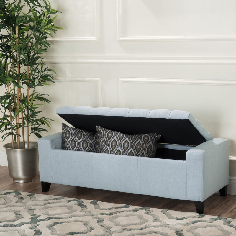 Noble House Guernsey storage ottoman with tufted top, beige fabric, and wooden legs, serving as stylish bedroom or living room storage.