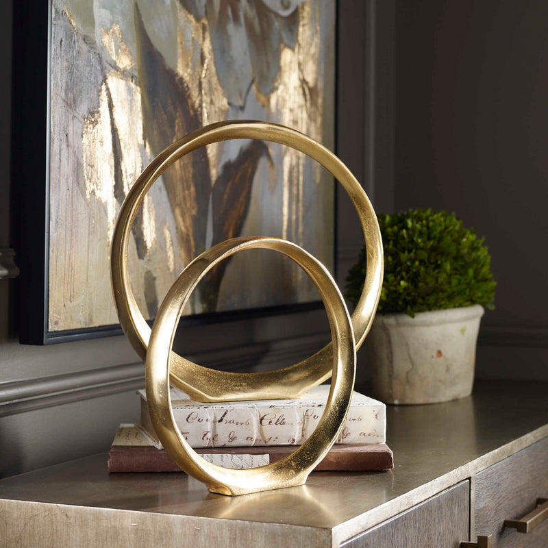 Pair of gold Jimena ring sculptures from Uttermost, decorative figurines with sleek, modern design for home decor.